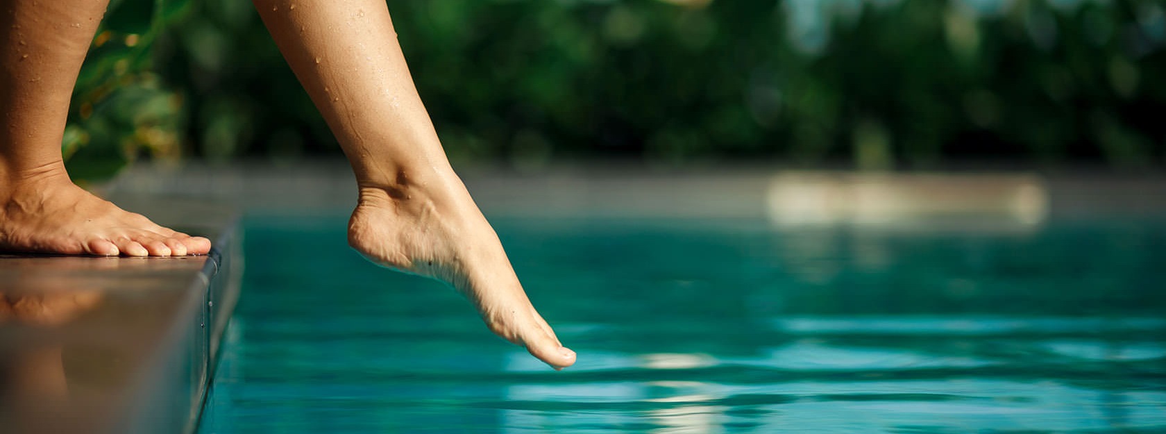 woman dipping toe in swimming pool